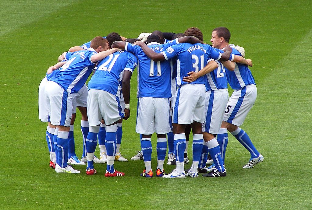 A group of soccer players huddle together on the field.