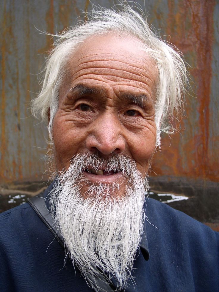 A man with white hair and beard smiling for the camera.