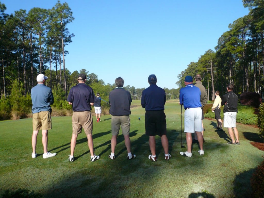 A group of people standing on top of a golf course.