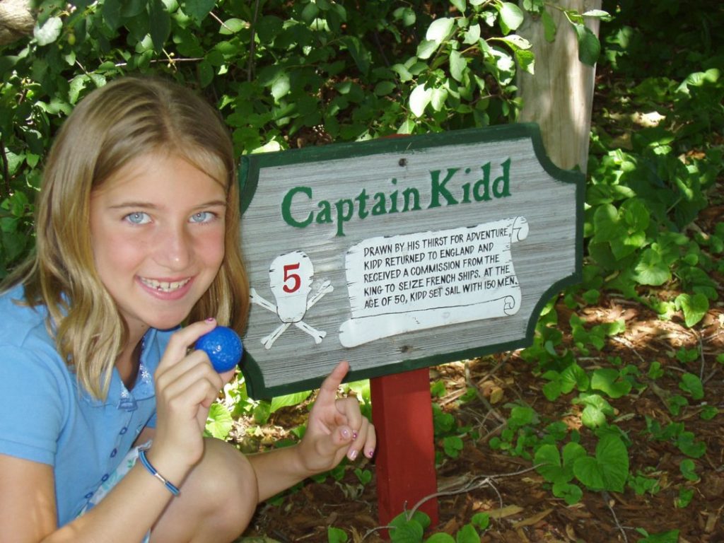 A girl holding a blue object in front of a sign.