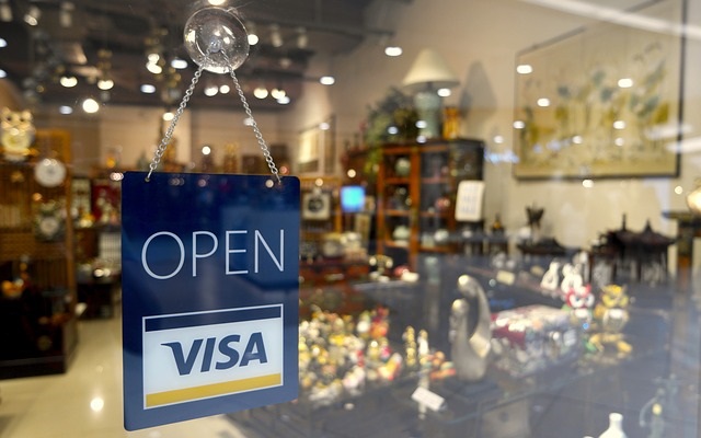 A sign that says open visa in front of a store window.