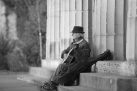 A man sitting on steps with his guitar.