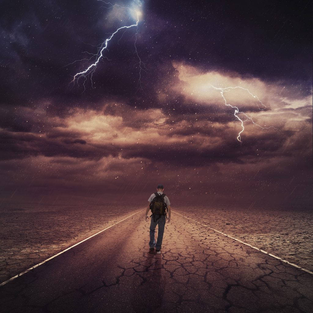A person walking down the road under a cloudy sky