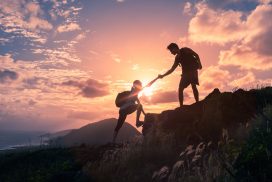 Two people are climbing a mountain at sunset.